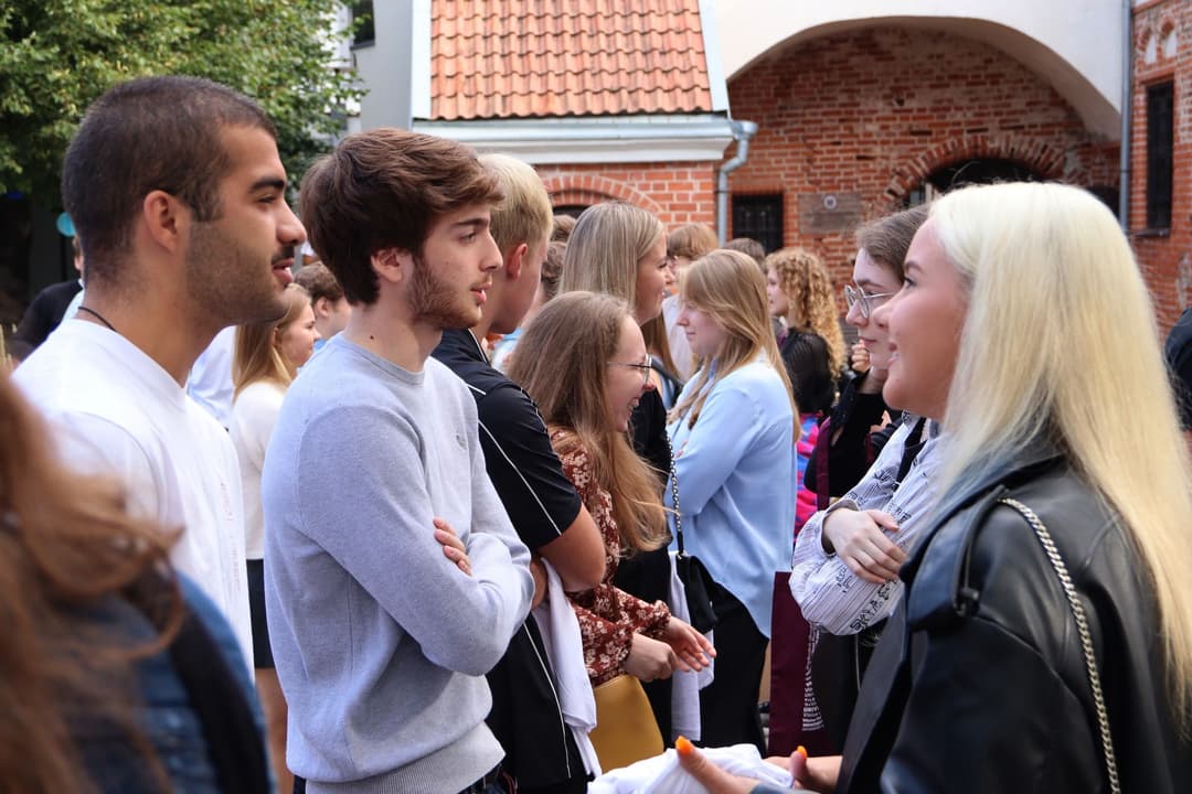 Students are playing a get-to-know-each-other game in the courtyard of the VU Kaunas Faculty.   